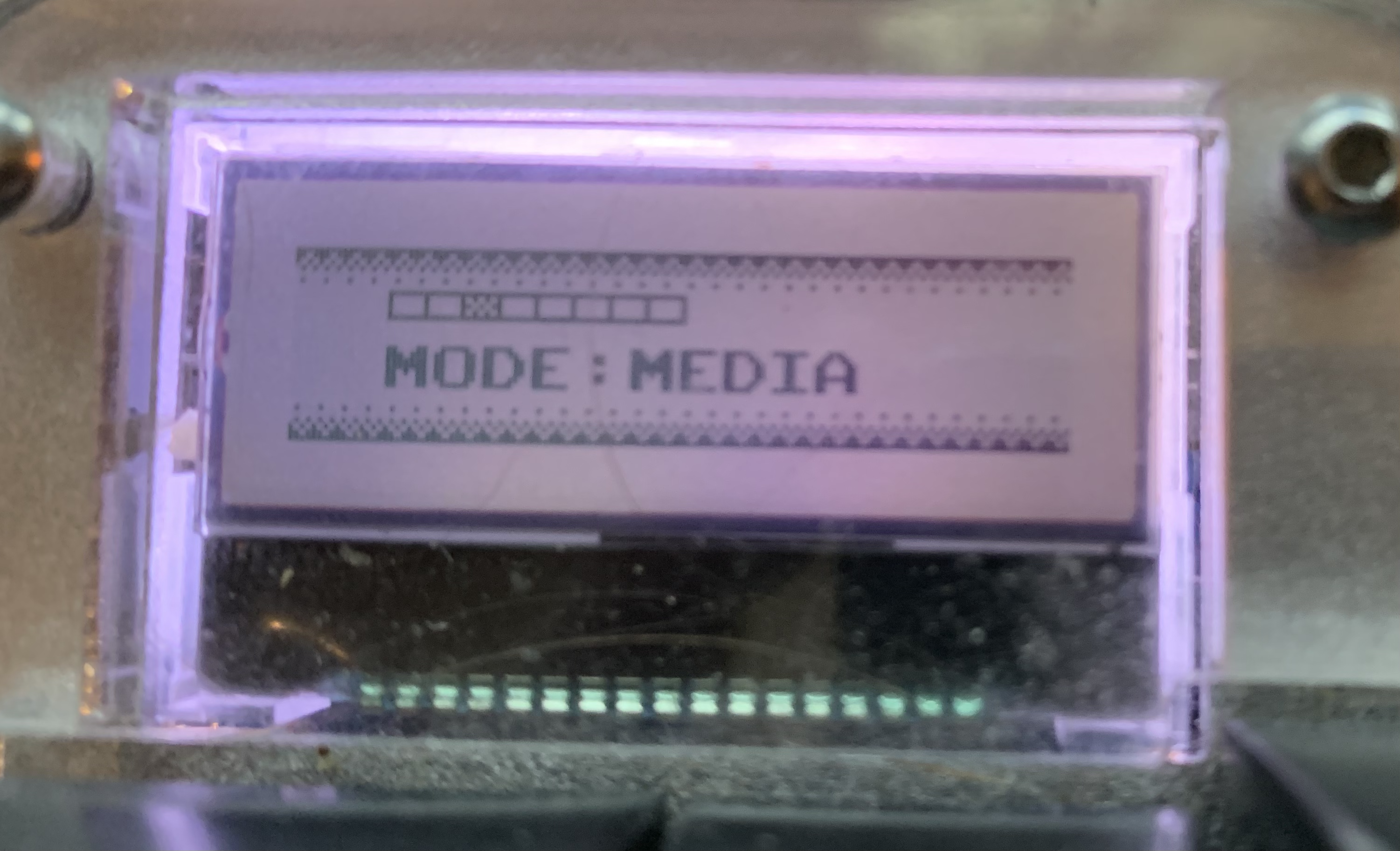 A photo of an LCD display showing the words "Mode: Media" with some pixel art styling.